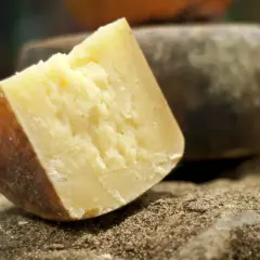 Kawałek twardego, żółtego sera, idealnego do pesto, leży na kamieniu obsypanym pieprzem.