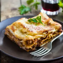 Pyszna lasagne z mielonym mięsem, idealna odpowiedź na pytanie: jakie mięso do lasagne. Podana na talerzu z widelcem.
