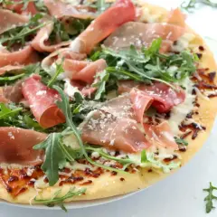 Pizza crudo z rukolą i parmezanem, pachnąca słońcem Włoch.