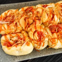 Pyszne bułeczki pizzowe z serem i kiełbaską, polane sosem pomidorowym i posypane ziołami. Idealne na przekąskę!