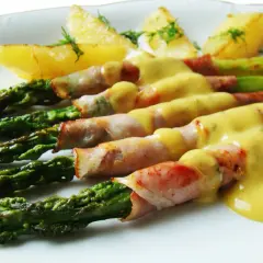 Zielone szparagi w szynce parmeńskiej, polane sosem, z pieczonymi ziemniakami. Pyszne danie.