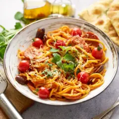 Pyszny makaron z chorizo, pomidorkami i świeżą bazylią, posypany parmezanem. Obok focaccia i oliwa.