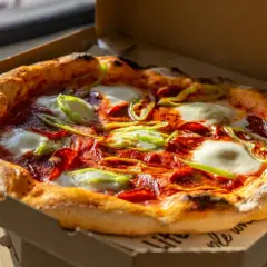 Pyszna pizza z pepperoni, mozzarellą i papryką, która przypomina o bogatej historii pizzy.