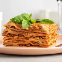 Pyszna, wielowarstwowa lasagne z mięsnym sosem i serem, udekorowana bazylią. Idealny przepis na obiad.