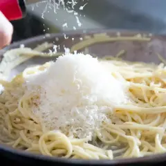 Szukając alternatywy dla parmezanu do pesto, dodaję starty ser do gorącego makaronu w patelni.