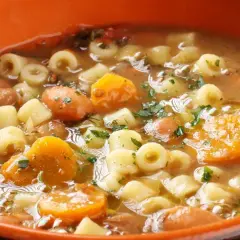 Gęsta, aromatyczna zupa minestrone z makaronem, fasolą, marchewką i ziemniakami, posypana natką pietruszki.