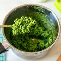 Łyżka świeżego, zielonego pesto bazyliowego nad metalowym garnkiem. Idealne do makaronu!