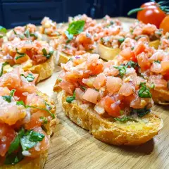 Pyszne bruschetta z pomidorami i bazylią, ułożone na drewnianej desce. Idealna przekąska na lato.
