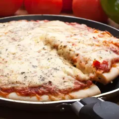 Pyszna pizza z patelni, z ciągnącym się serem i aromatycznymi ziołami, gotowa do podania.