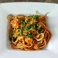 Pyszne spaghetti z owocami morza, krewetkami i kalmarami, posypane świeżą natką pietruszki.