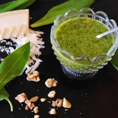 Zielony sos mojo verde w miseczce, obok ser, orzechy i liście dzikiego czosnku.