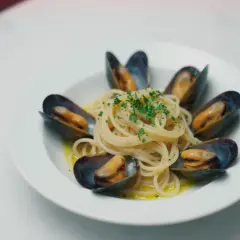 Spaghetti z małżami, danie pełne smaku morza, ozdobione świeżą natką pietruszki.