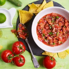 Świeża salsa pomidorowa z cebulą i kolendrą, podana z nachos i limonką. Idealna do meksykańskich potraw.