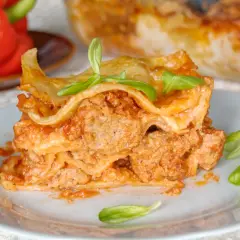 Pyszna porcja lasagne napoli z mięsem mielonym i sosem pomidorowym, udekorowana listkami bazylii.