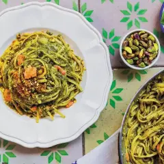 Pyszne linguine z zielonym pesto i kawałkami łososia, posypane pistacjami. Różnorodne kształty makaronu tworzą apetyczną całość.