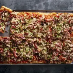 Pyszna pizza domowa przepis na blachę, obficie posypana pieczarkami, szynką i serem. Idealna na rodzinne spotkanie.