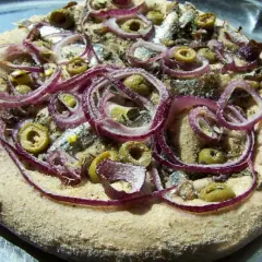 Pizza z anchois, oliwkami i czerwoną cebulą na chrupiącym cieście.