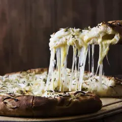 Rozpływający się ser ciągnie się z kawałka pizzy quattro formaggi, tworząc apetyczny widok.