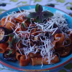 Pyszne danie pasta alla norma z makaronem rigatoni, bakłażanem w sosie pomidorowym i posypane startym serem.