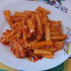 Pyszny makaron z sosem pomidorowym na białym talerzu, gotowy do zjedzenia.