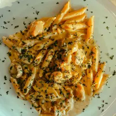 Penne w kremowym sosie z kurczakiem i pieczarkami, posypane natką pietruszki. Pyszny makaron, z którego jest zrobiony, zachwyca smakiem.