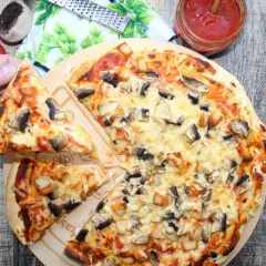 Pyszna pizza domowa z pieczarkami i kurczakiem, właśnie wyjęta z pieca. Ktoś właśnie bierze pierwszy kawałek.