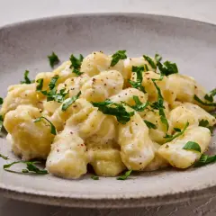 Puszyste gnocchi z serem, polane kremowym sosem i posypane świeżą natką pietruszki. Idealne danie dla miłośników włoskich smaków.