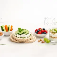 Zdrowe przekąski: miseczki z migdałami, warzywami, owocami, jogurt z granolą i kiwi, ryżowe wafle z twarożkiem i ogórkiem.