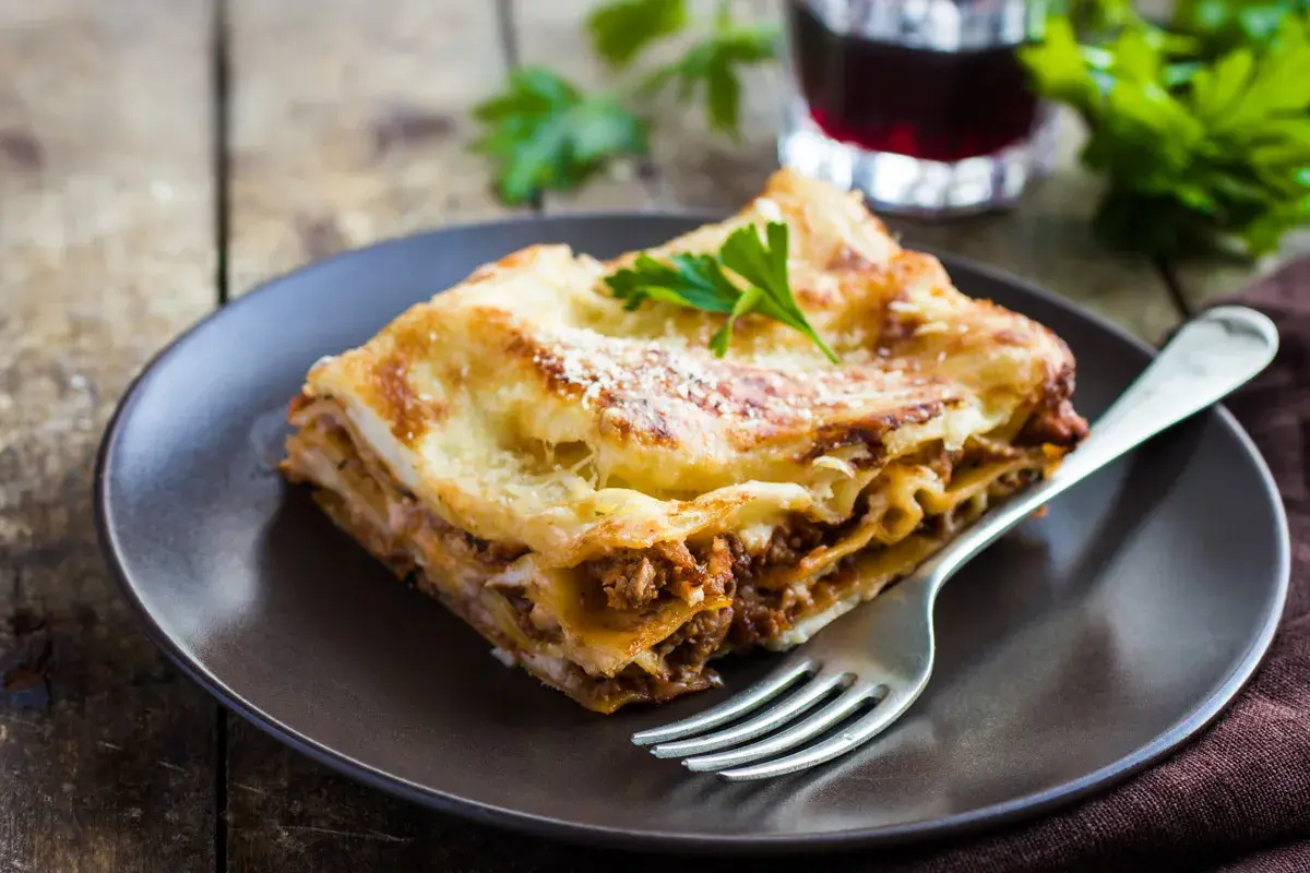 Pyszna lasagne z mielonym mięsem, idealna odpowiedź na pytanie: jakie mięso do lasagne. Podana na talerzu z widelcem.