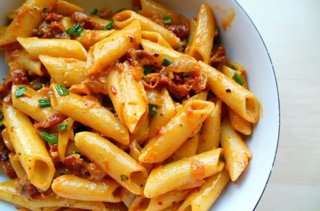 Penne z sosem z suszonych pomidorów i zieloną cebulką, apetyczne danie pełne smaku.