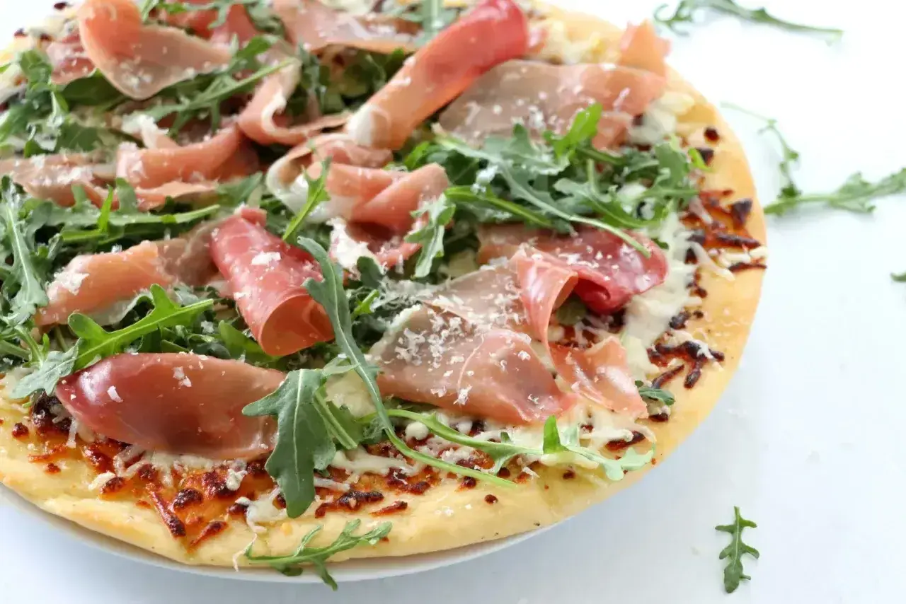 Pizza crudo z rukolą i parmezanem, pachnąca słońcem Włoch.