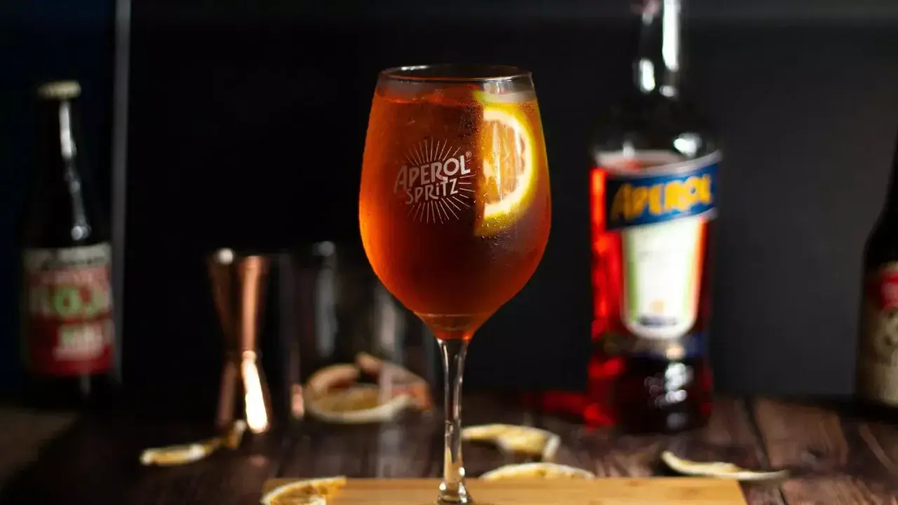 Orzeźwiający Aperol Spritz z plastrem pomarańczy. Idealny aperitif, który możesz łatwo przygotować w domu. Poznaj nasz prosty aperol przepis!