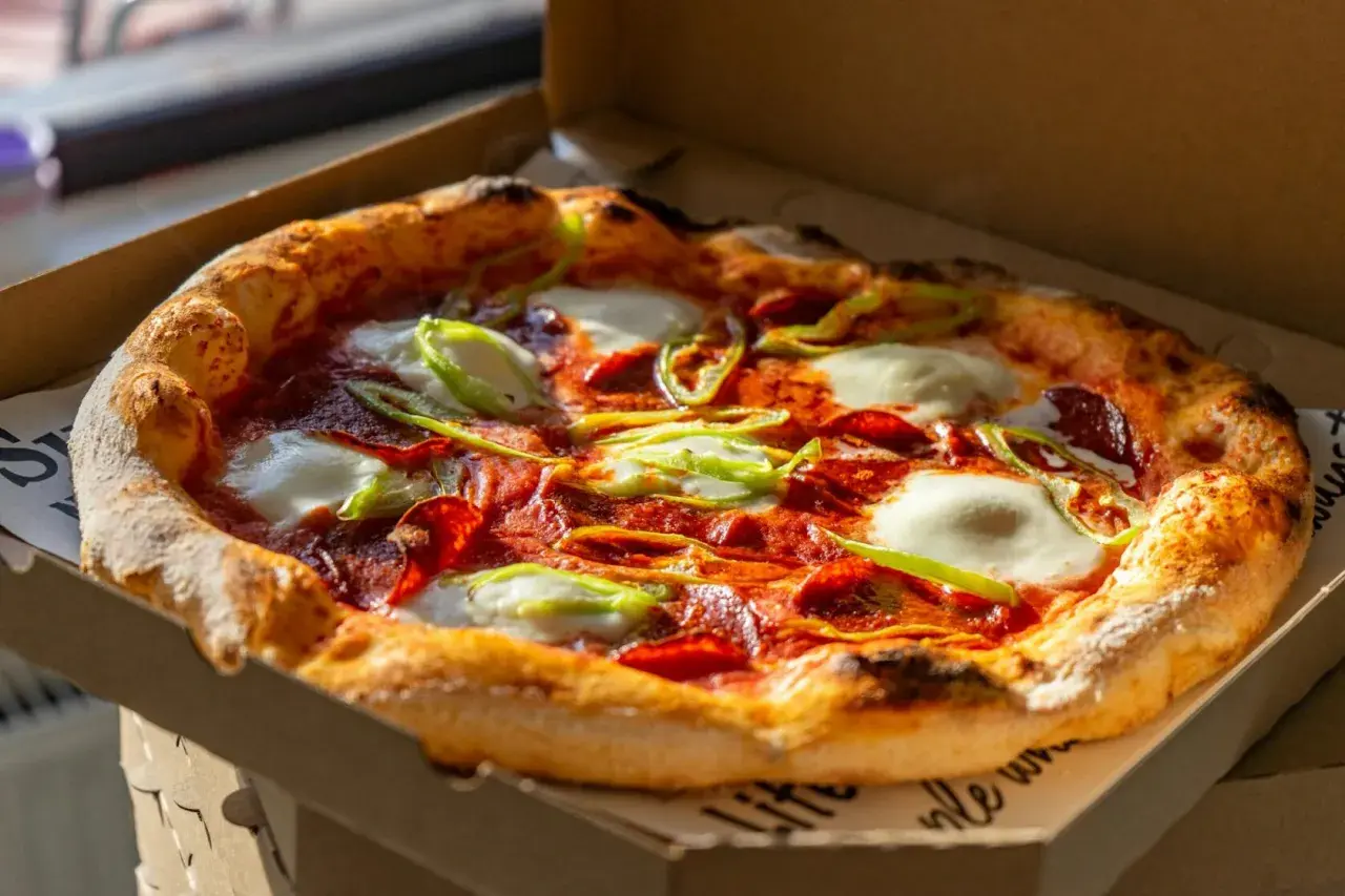 Pyszna pizza z pepperoni, mozzarellą i papryką, która przypomina o bogatej historii pizzy.