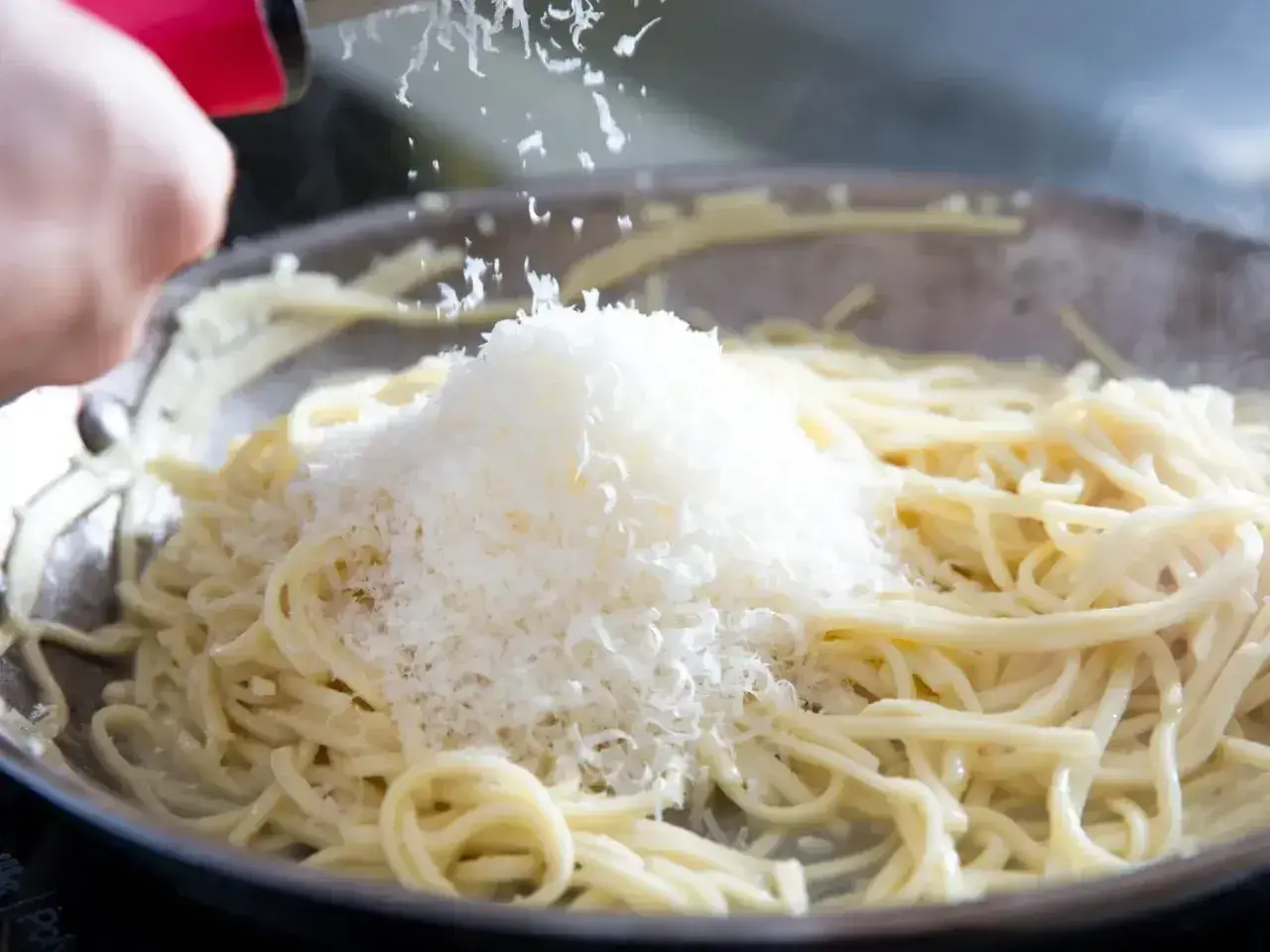 Szukając alternatywy dla parmezanu do pesto, dodaję starty ser do gorącego makaronu w patelni.