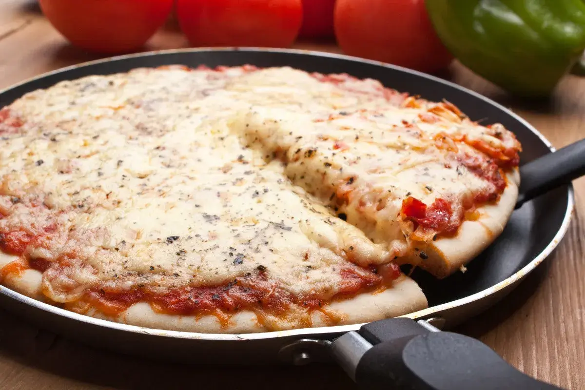 Pyszna pizza z patelni, z ciągnącym się serem i aromatycznymi ziołami, gotowa do podania.