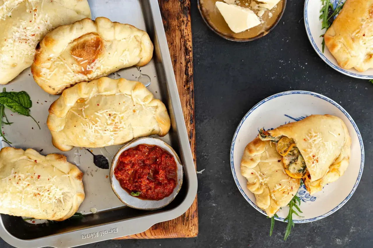 Mini calzone przepis: złociste, pieczone pierożki z serem i ziołami, podane z sosem pomidorowym. Idealne na przekąskę.