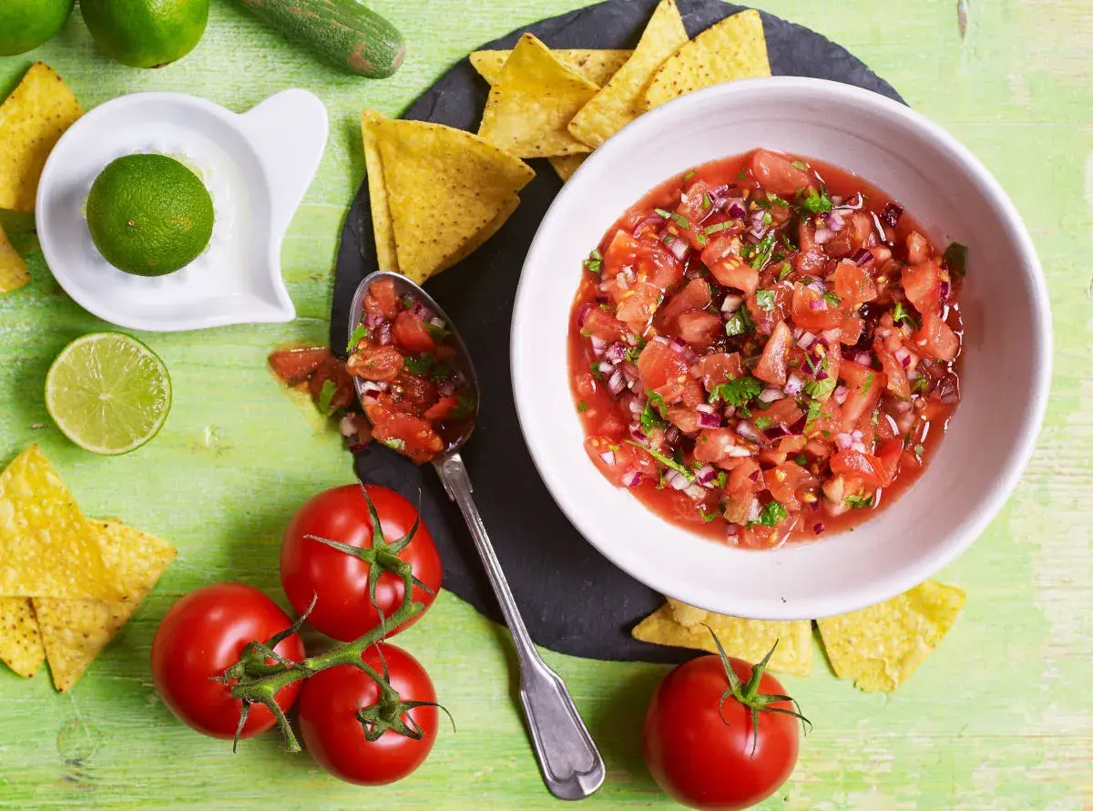 Świeża salsa pomidorowa z cebulą i kolendrą, podana z nachos i limonką. Idealna do meksykańskich potraw.