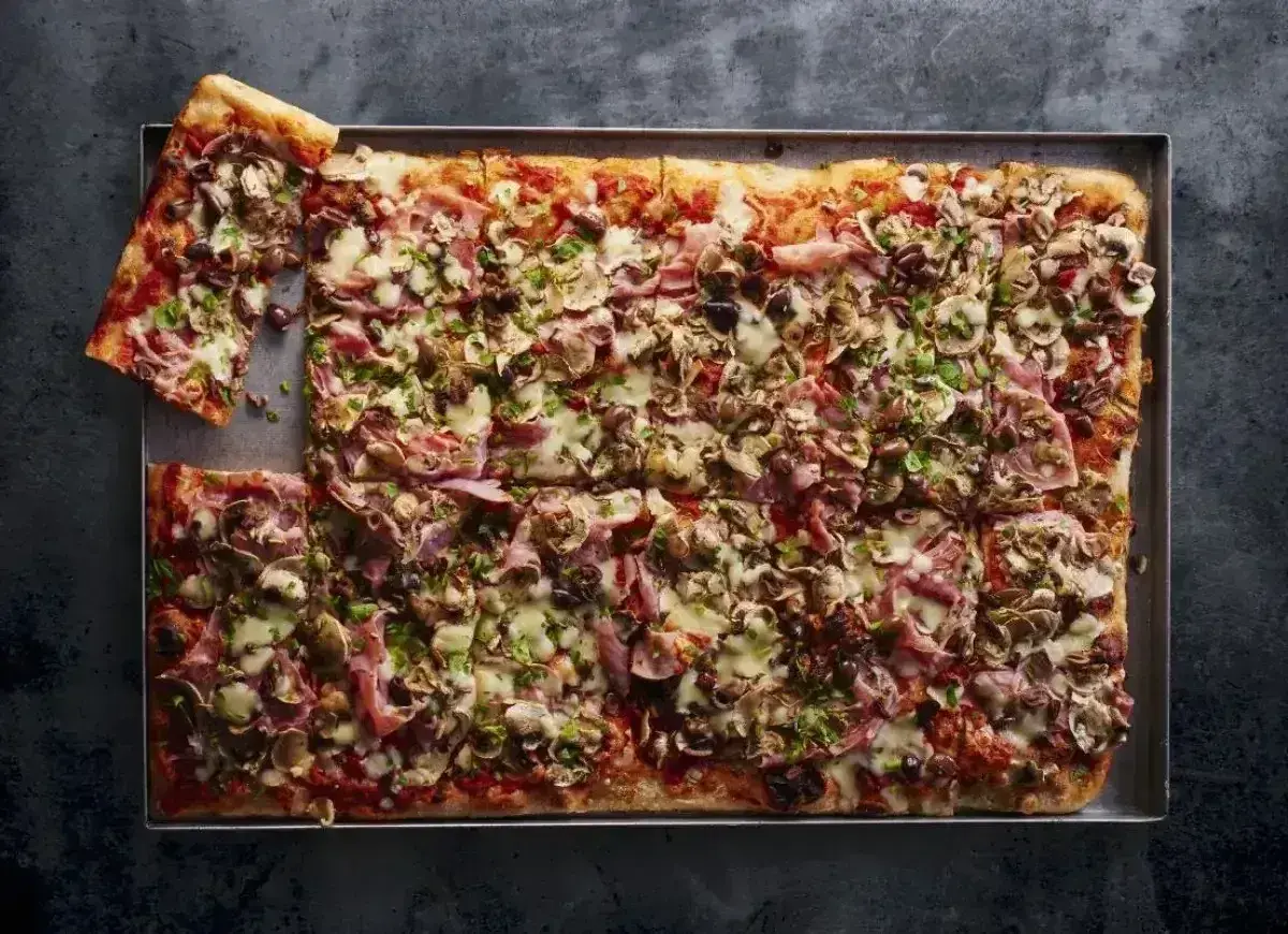 Pyszna pizza domowa przepis na blachę, obficie posypana pieczarkami, szynką i serem. Idealna na rodzinne spotkanie.