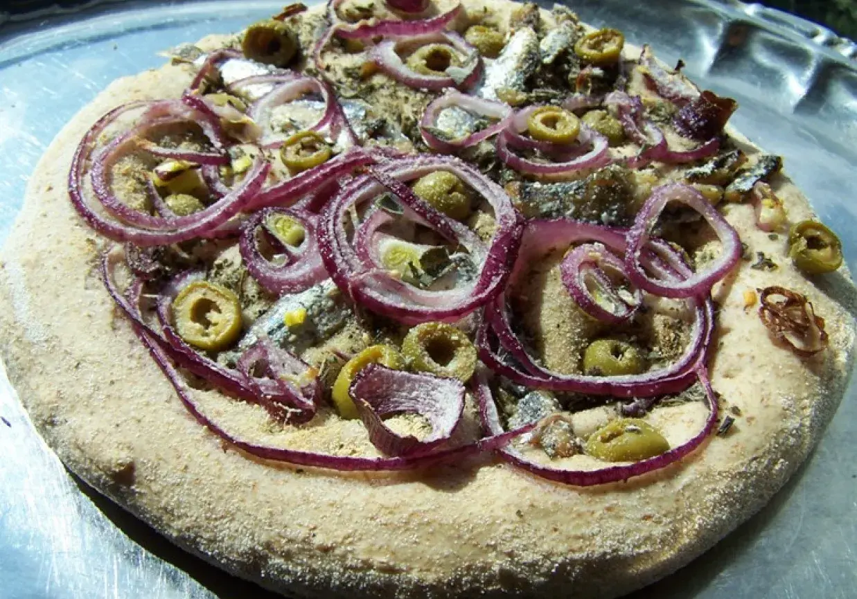 Pizza z anchois, oliwkami i czerwoną cebulą na chrupiącym cieście.