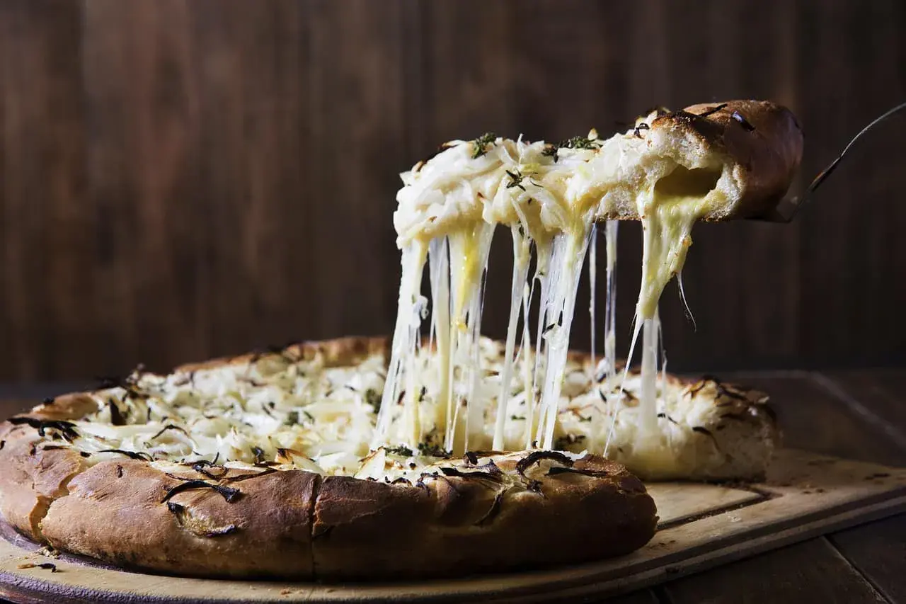 Rozpływający się ser ciągnie się z kawałka pizzy quattro formaggi, tworząc apetyczny widok.