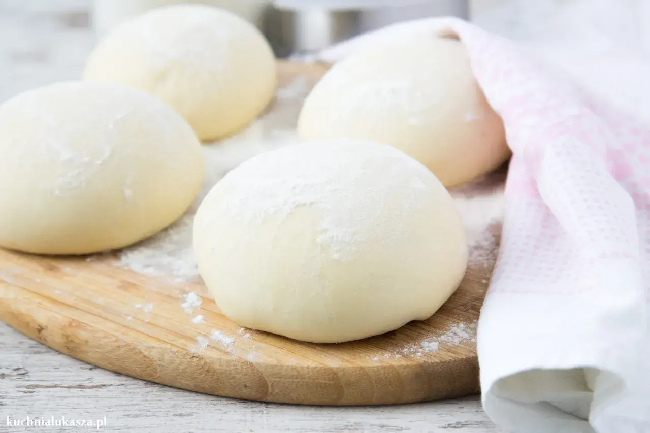 Kulki ciasta na desce, gotowe na idealne ciasto na pizzę. Lekko oprószone mąką, czekają na swoją kolej.