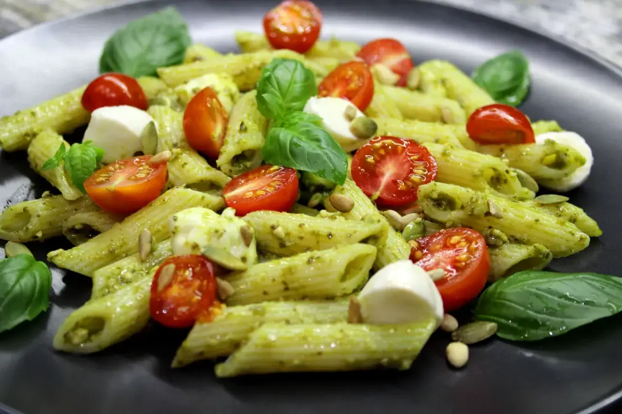 Penne z pesto bazyliowym, pomidorkami koktajlowymi i mozzarellą. Idealne danie, by pokazać, z czym jeść pesto bazyliowe.