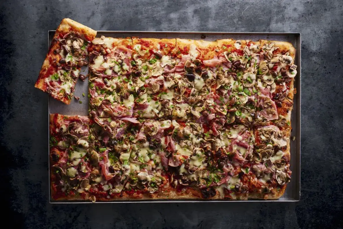 Domowa pizza na blachę z szynką, pieczarkami i oliwkami. Idealna na rodzinne spotkanie, łatwy przepis.