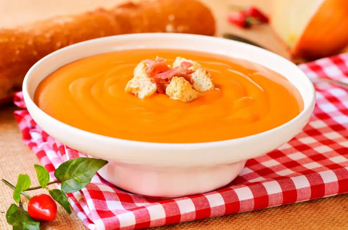 Pomarańczowe gazpacho z grzankami i szynką, idealne na lato. Prosty przepis na orzeźwiające danie.