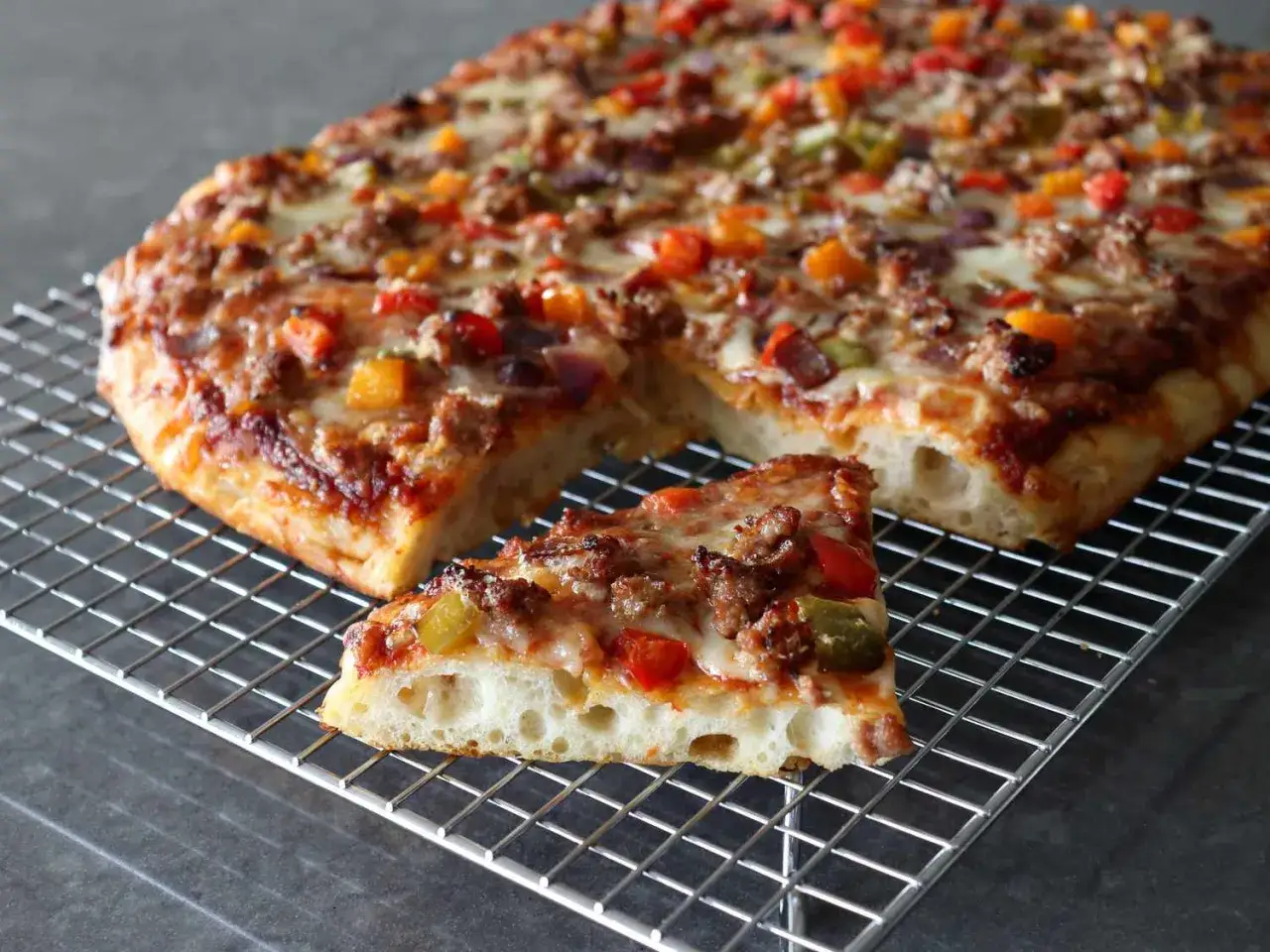 Pyszna pizza rzymska z mięsem mielonym i warzywami, z chrupiącym ciastem, na metalowej kratce.