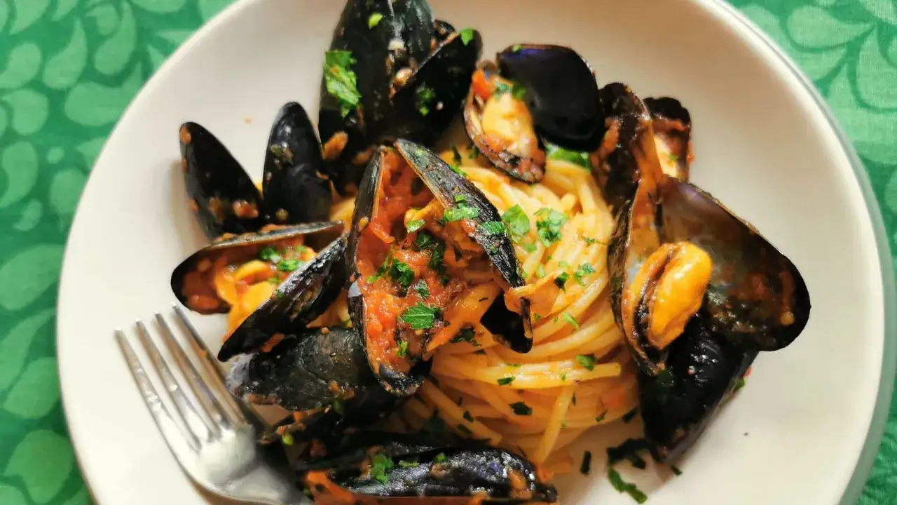 Pyszne spaghetti z soczystymi małżami w sosie pomidorowym. Idealna pasta z owocami morza na letni obiad.