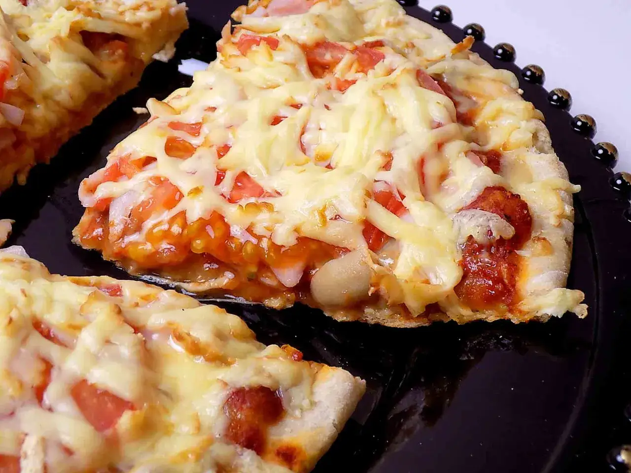 Pyszna pizza z patelni z ciągnącym się serem i kawałkami pomidorów. Idealna na szybki obiad.