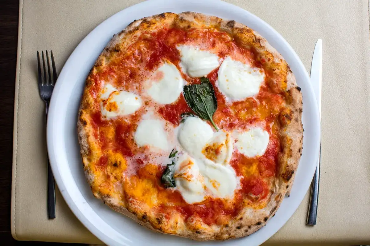 Pyszna pizza włoska z pomidorami, mozzarellą i bazylią, gotowa do zjedzenia.
