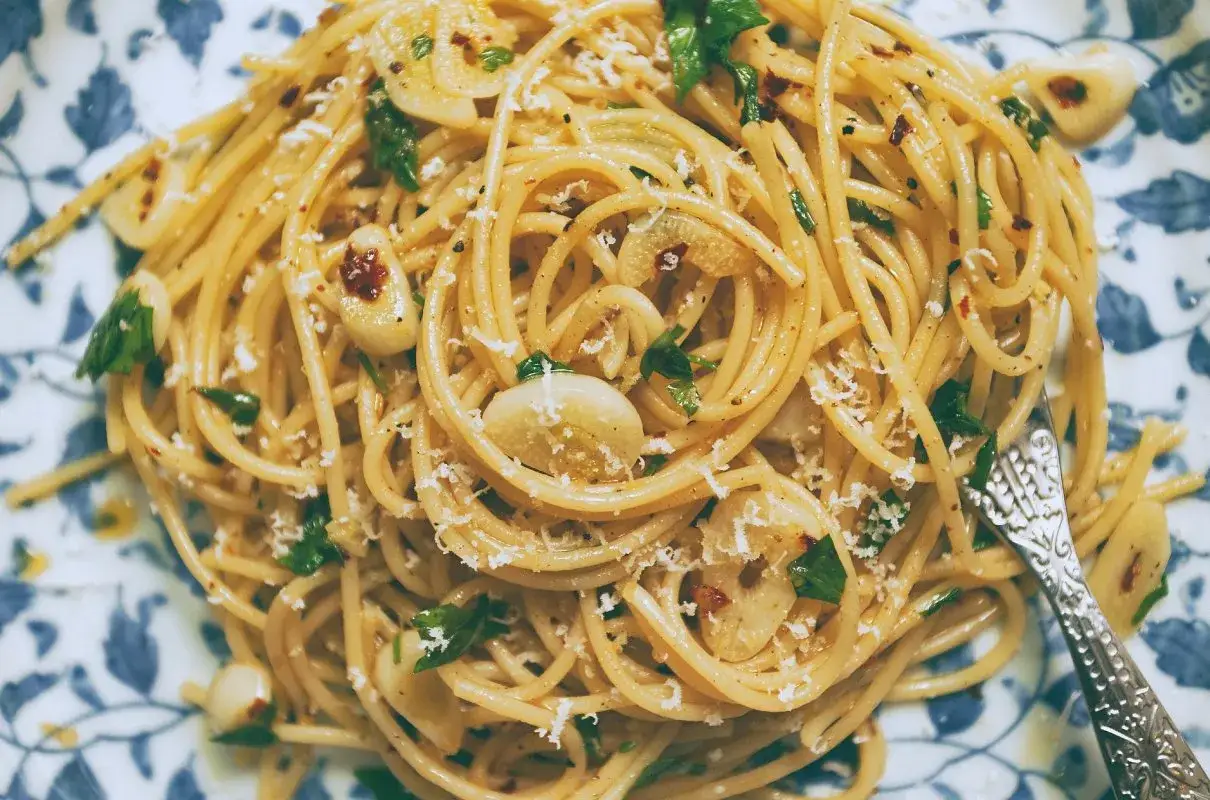 Pyszne spaghetti aglio e olio z czosnkiem, natką pietruszki i płatkami chili, posypane parmezanem.