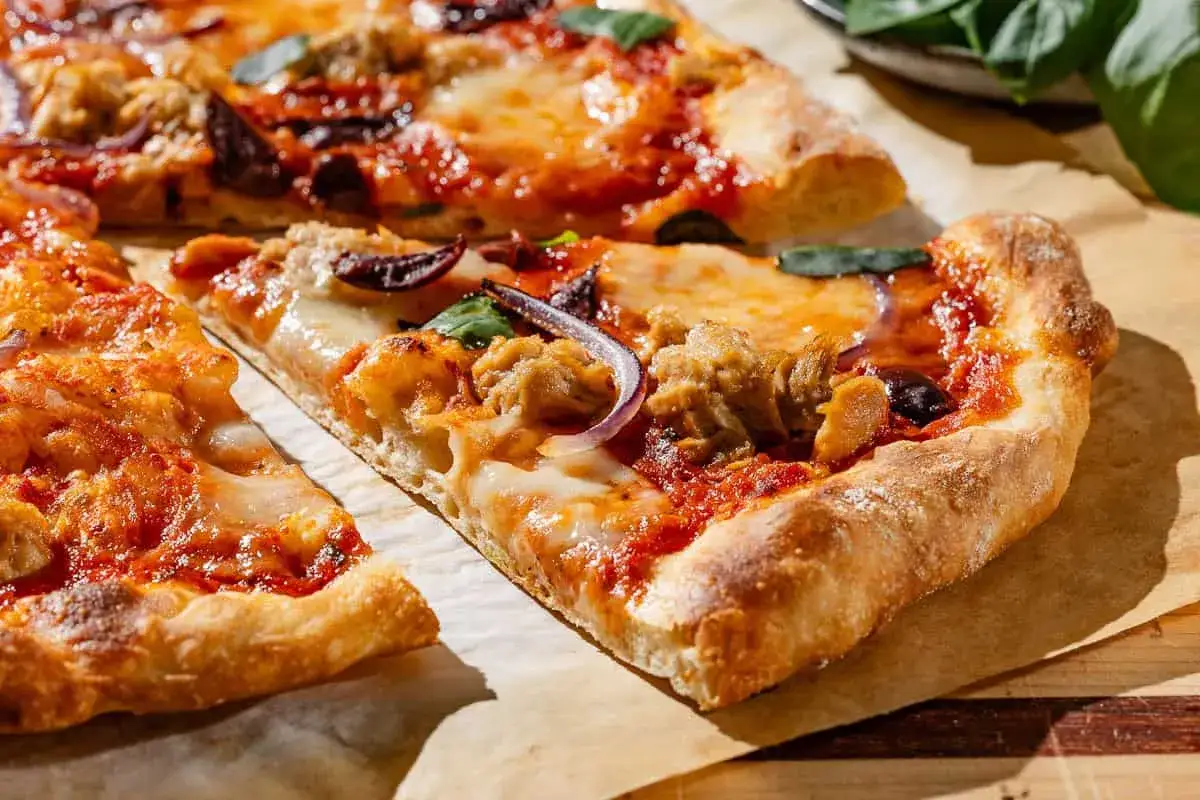 Kawałek pysznej pizzy z tuńczykiem, mozzarellą, czerwoną cebulą i oliwkami. Idealna na szybki obiad.
